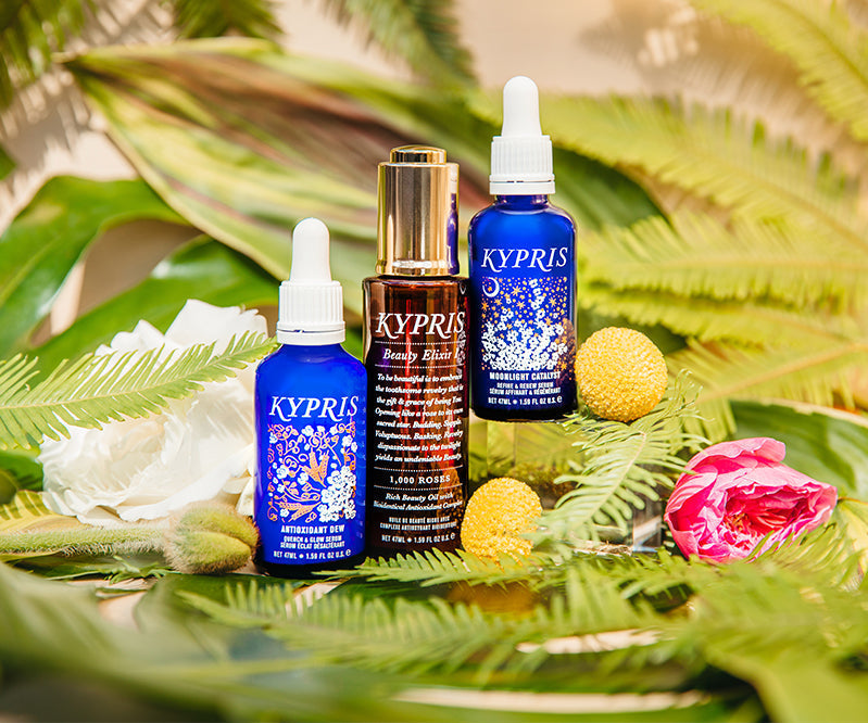 KYPRIS Antioxidant Dew, Beauty Elixir & Nightlight Catalyst serums with floral and leafy backdrop