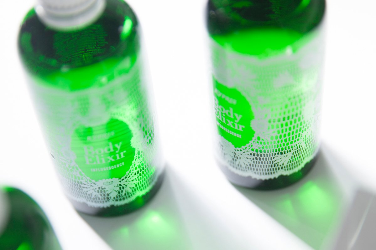 KYPRIS Body Elixir Inflorescence in green glass bottles with lace-patterned labels on white surface
