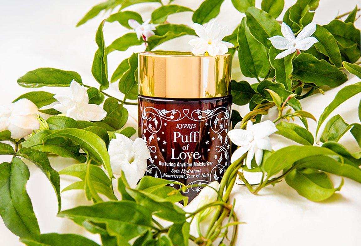 KYPRIS Puff of Love Nurturing Anytime Moisturizer surrounded by fresh jasmine flowers and green leaves