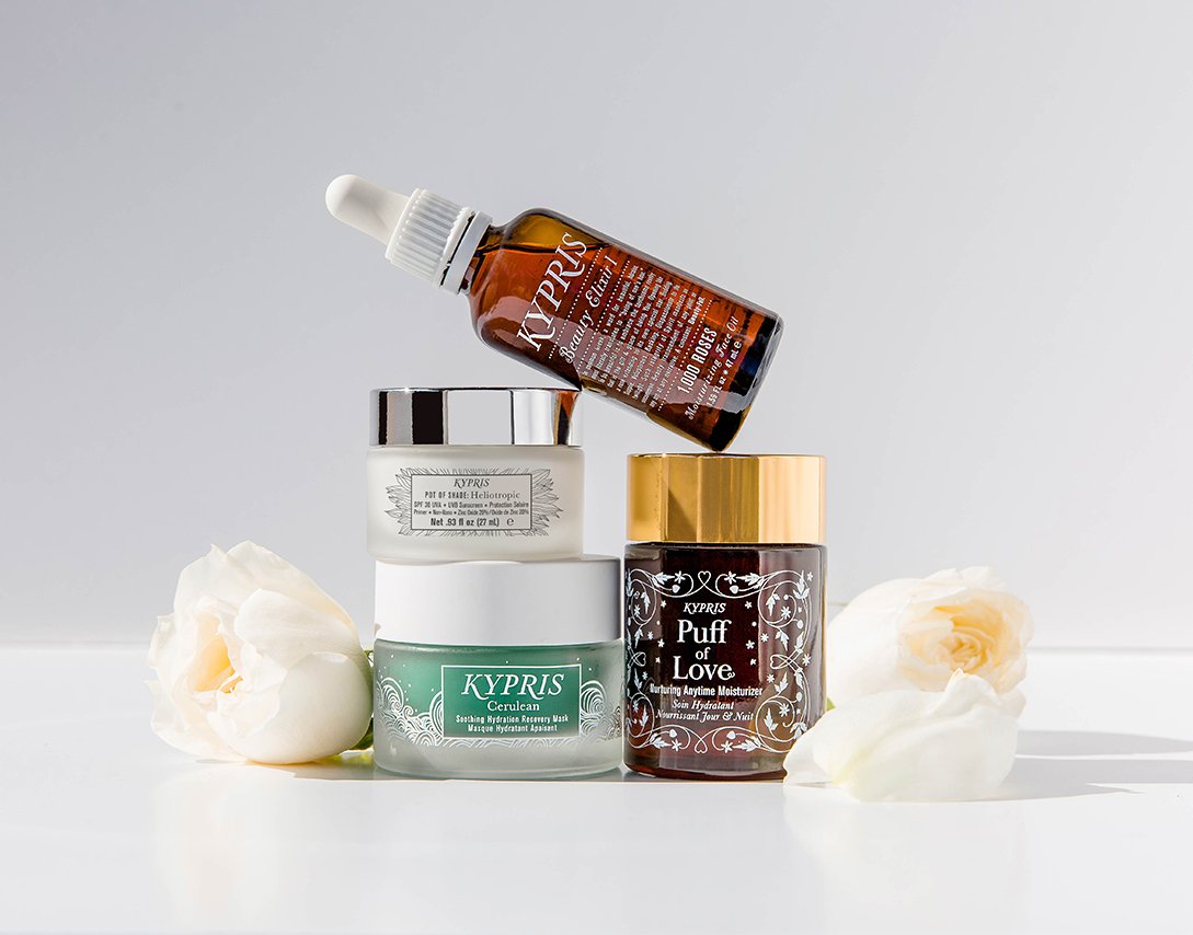 KYPRIS Beauty Elixir, Pot of Shade, Cerulean, and Puff of Love skincare products with white roses