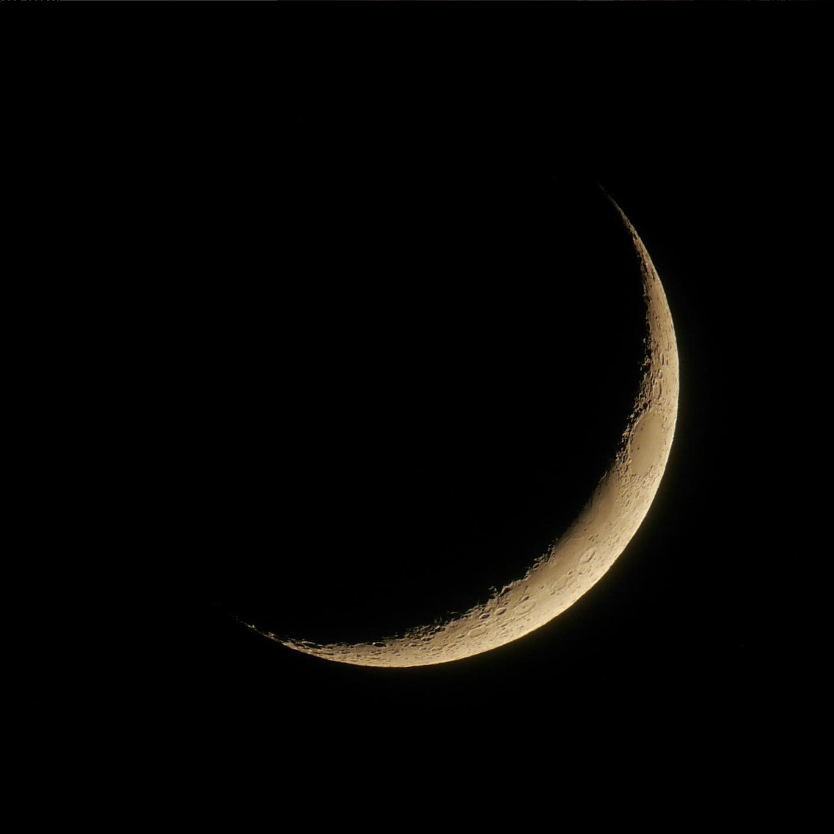 Crescent moon against dark sky, showing detailed craters and lunar surface texture