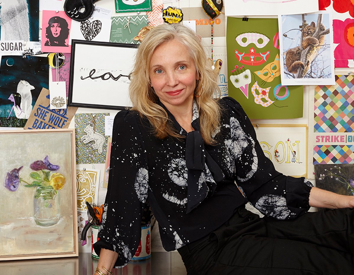 Woman in black splatter blouse surrounded by colorful art and posters