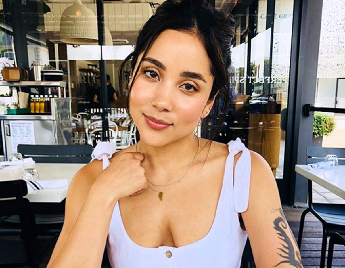 Woman in white top at outdoor cafe with tattoo on arm