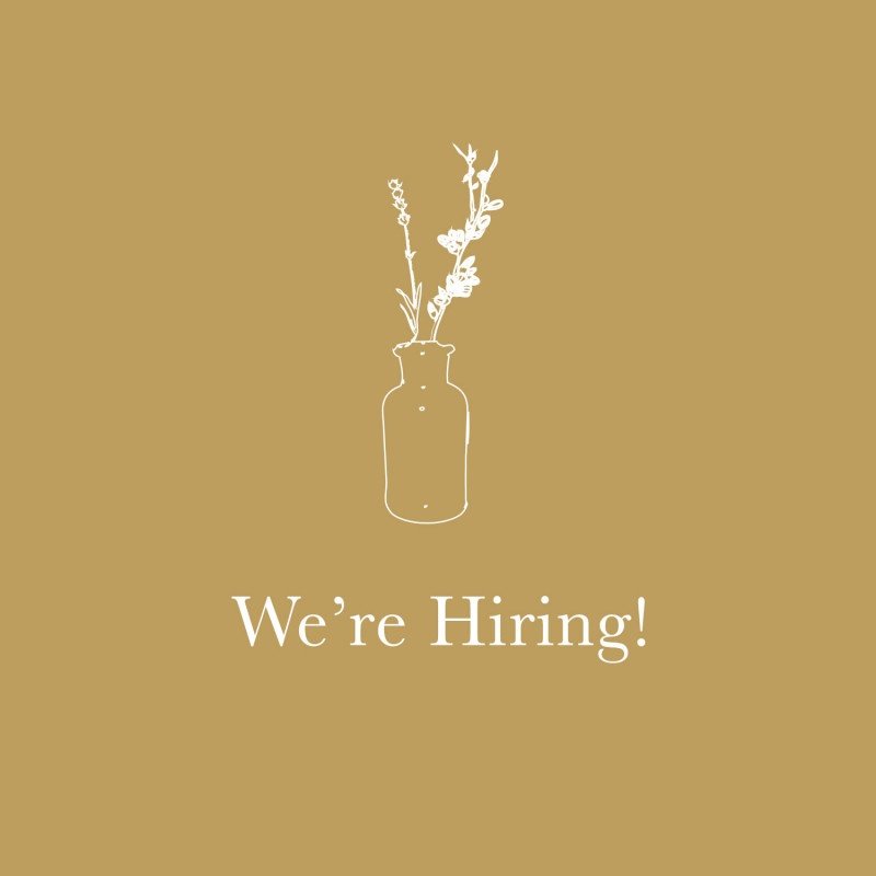 We're Hiring! with white floral illustration on gold background