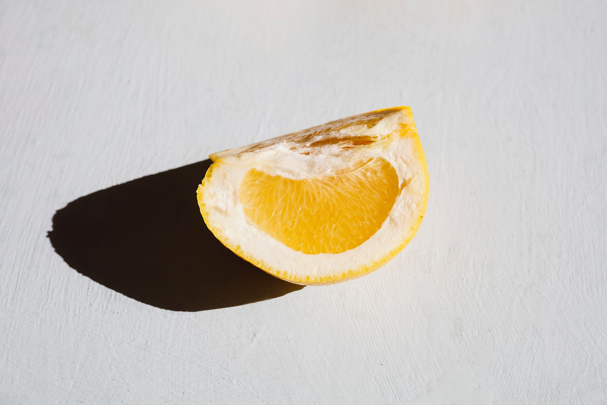 Orange slice casting a shadow on a white background.