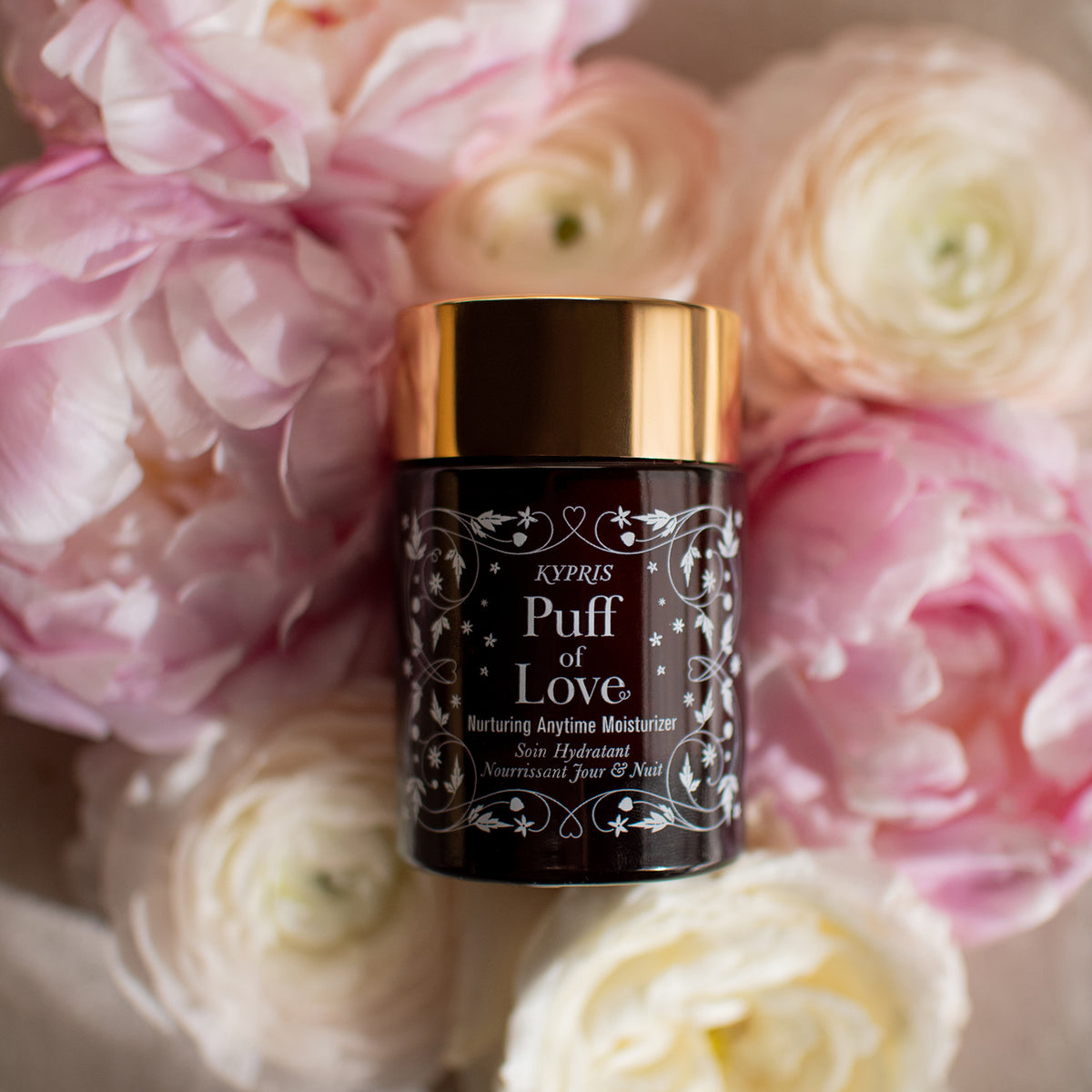 Puff of Love Nurturing Anytime Moisturizer Resting on a Bed of Ranunculus